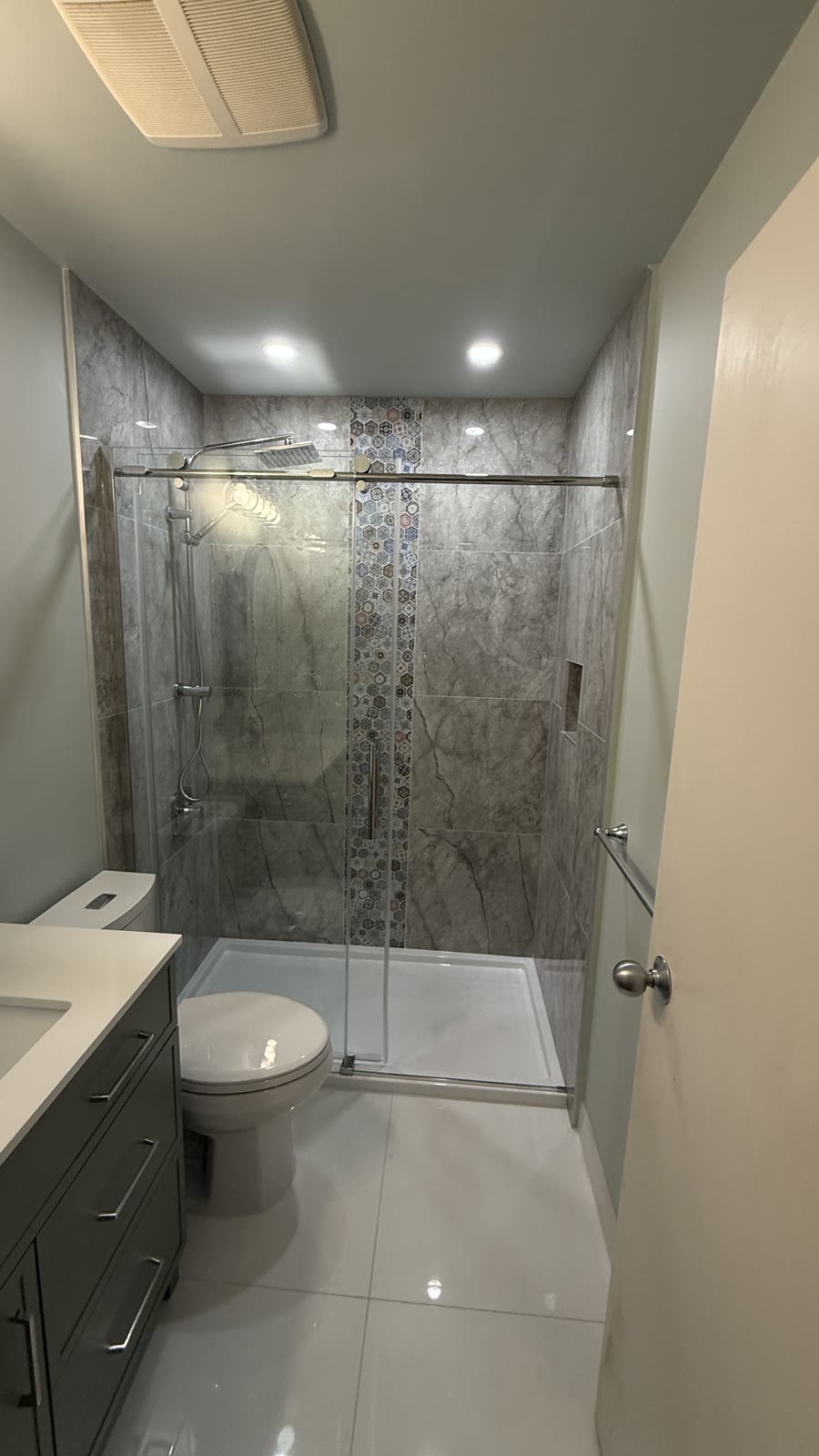 Completed large-format tile shower renovation with accent strip by Budova